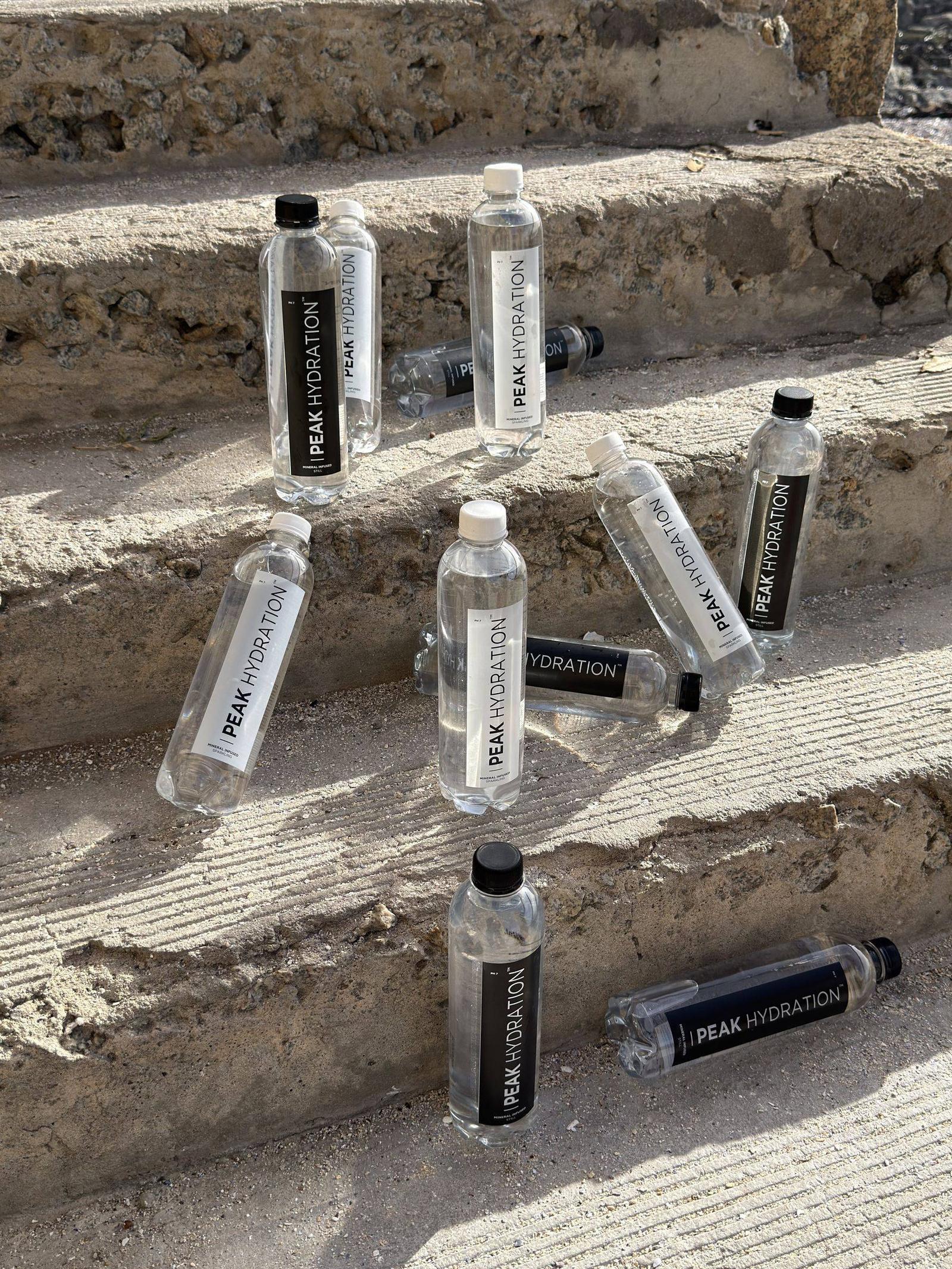 Peak Hydration bottles scattered across sunlit concrete steps