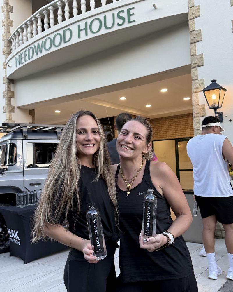 Two women holding Peak Hydration outside Heedwood House