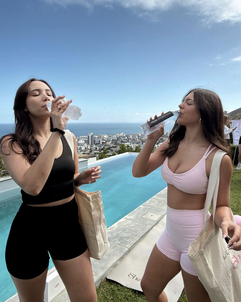 Two women drinking Peak Hydration by the pool