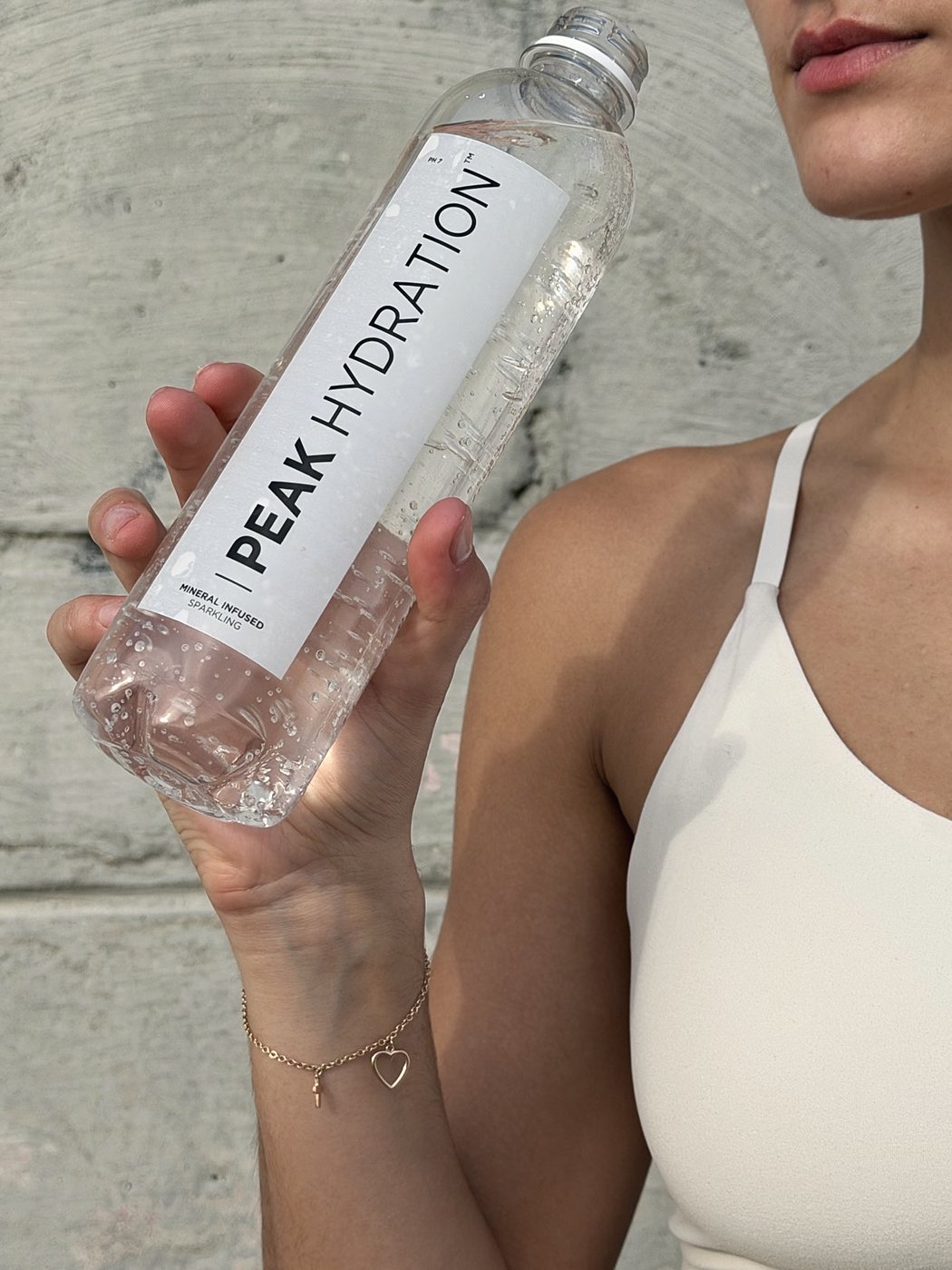 Holding a bottle of Peak Hydration sparkling after training